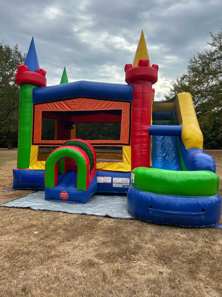 Multicolor castle bounce house combo with slide set up on a lawn in Whitesboro, TX