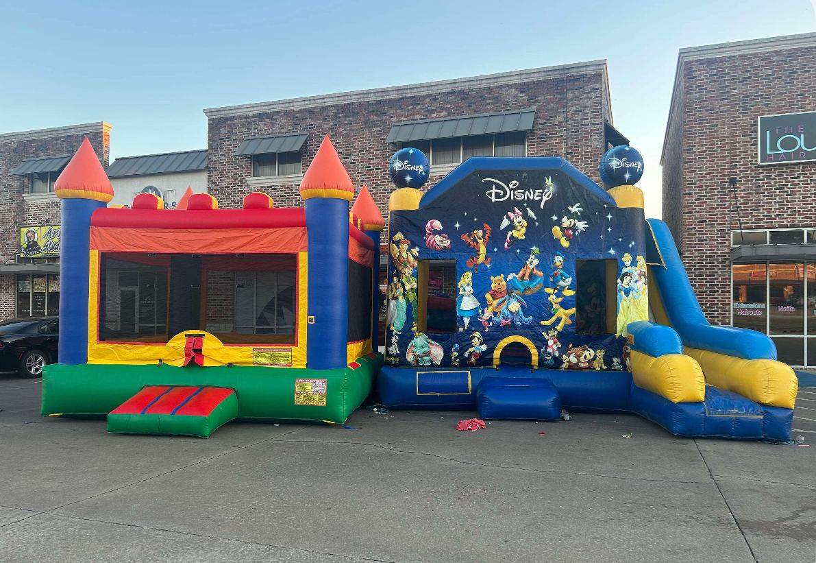Castle bounce house and a character-themed combo with slide set up side by side on a paved commercial lot in Durant, OK
