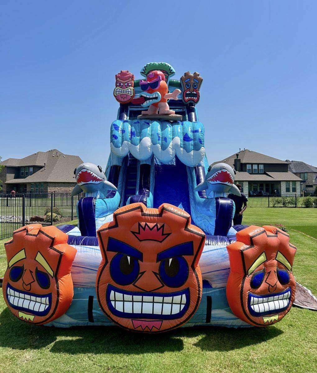 Tall tiki-themed tropical dual-lane water slide set up on a fenced backyard lawn in Gunter, TX