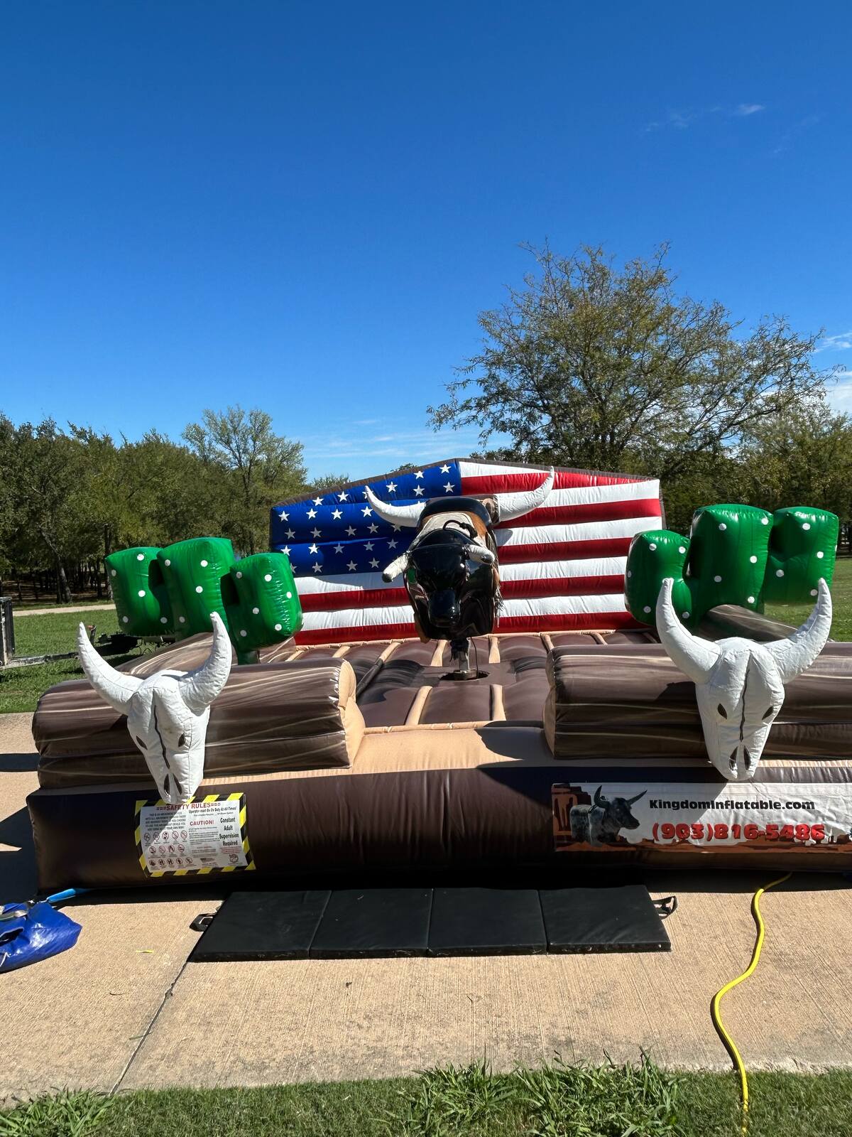 Mechanical bull rental set up in front of an American flag backdrop in Sherman, TX