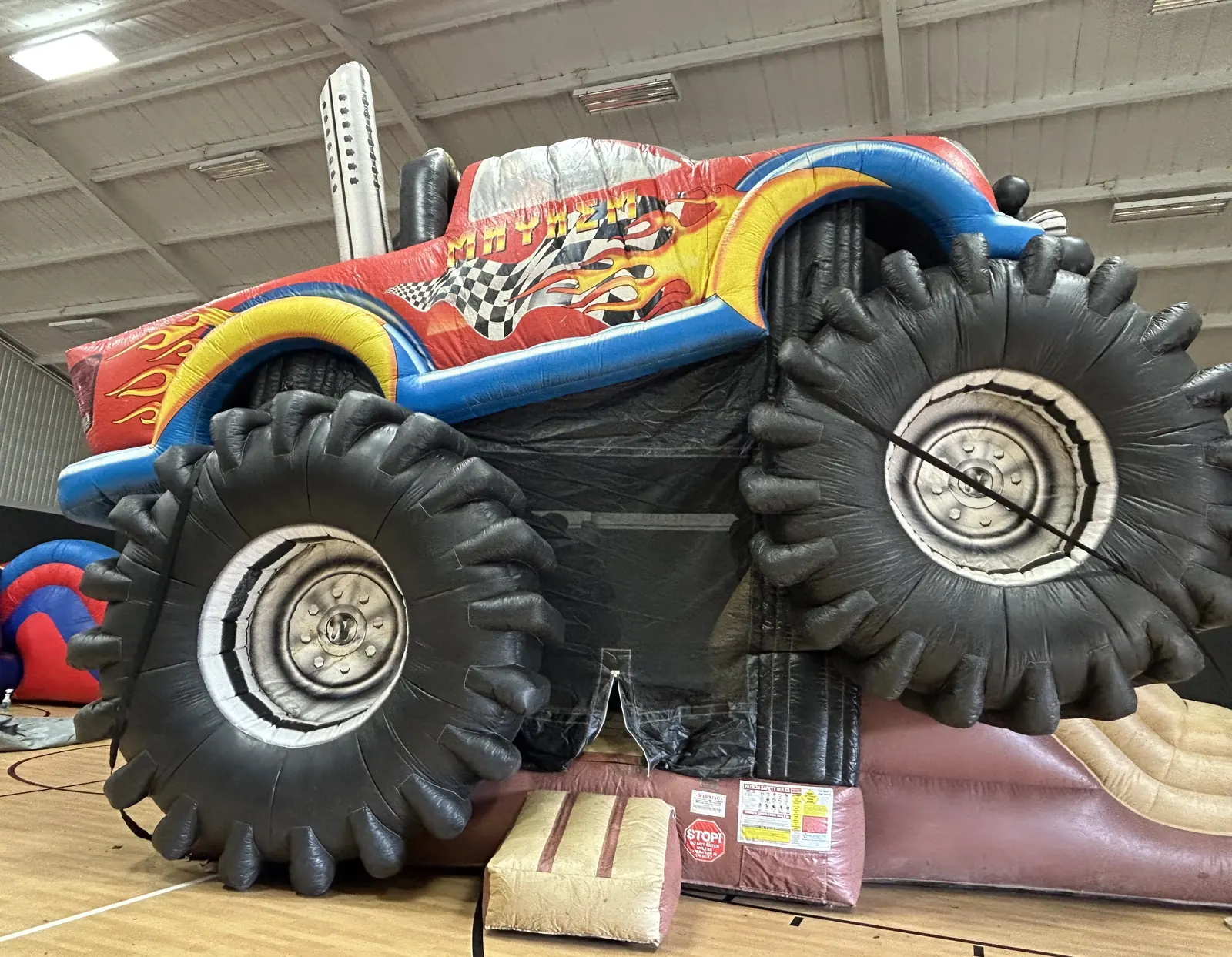 Monster truck bounce house combo with slide set up indoors on a gym basketball court in Howe, TX