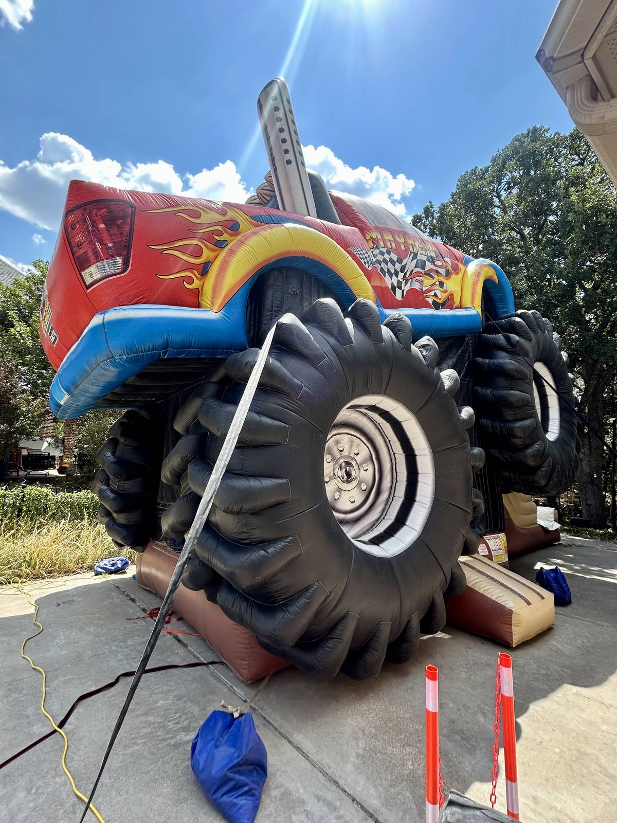 XL Monster Truck combo bounce house on a concrete driveway secured with sandbags in Pottsboro, TX