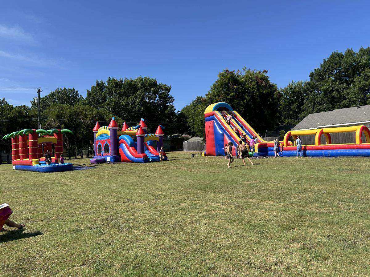 Several inflatables, including bounce house combos and a water slide, set up across an open grass field for a party in Whitesboro, TX
